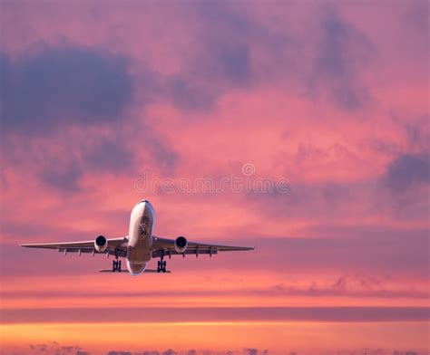 Passenger Airplane Is Flying In Colorful Sky At Sunset Stock Photo
