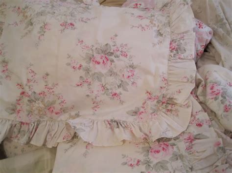 A Bed With Pink Flowers And Ruffles On It