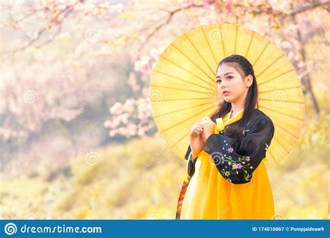 Korean Girl Wearing A Hanbok Wearing A Yellow Umbrella. Beautiful Female Wearing Traditional 
