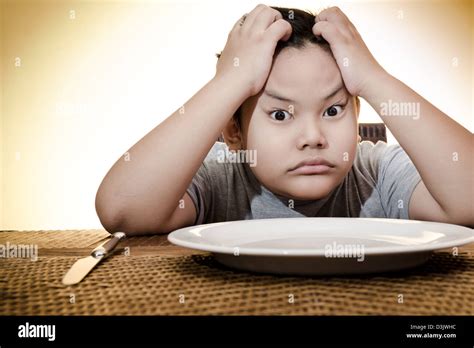Asian Boy Sitting Sadly On Dining Table Waiting For Food Looking At