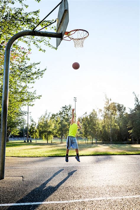 Asian Kid Shooting Basketball In An Outdoor Basketball Court By