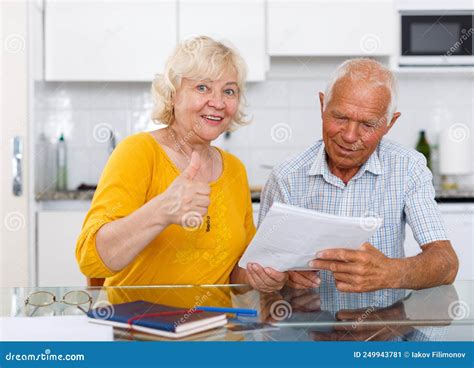 Mature Couple In Home Interior Filling Up Documents At Home Stock Image
