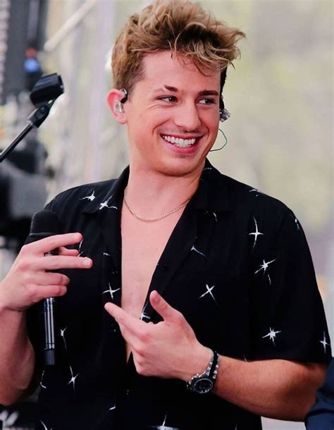 A Man Standing In Front Of A Microphone With His Hand On His Hip And Smiling At The Camera