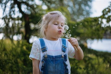 Premium Photo Pretty Little Girl Blowing Off Dandelion Seeds On