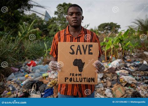 A Boy Holds A `save Africa From Pollution` Sign And Stands By An