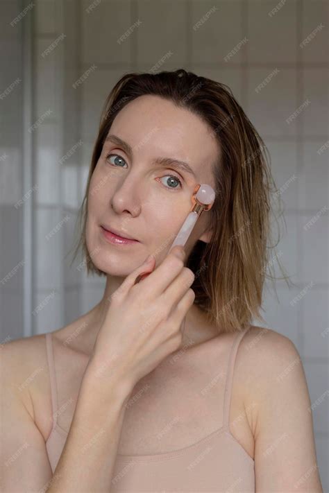 Premium Photo Woman Massages Her Face With Rose Quartz Massager Self
