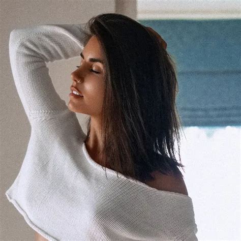 A Woman With Long Hair Is Wearing A White Sweater And Posing In Front