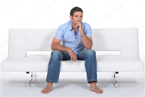 Barefoot Man Sitting On A Modern Couch And Wondering Stock Photo