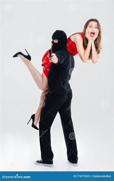 Man In Balaclava Stealing Woman And Pointing Gun On You Stock Image