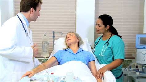 hospital doctor and nurse giving medical care to mature female patient stock footage video