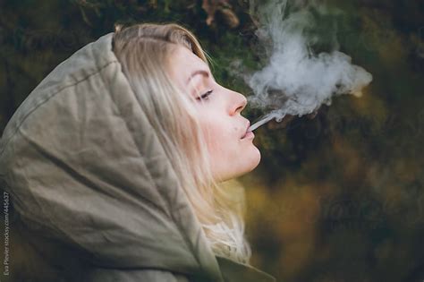 Young Blonde Woman With A Hood On Blowing Smoke Out Her Mouth By Eva