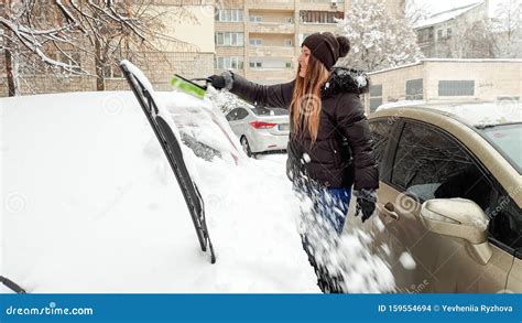 Closeup Shot Of Smiling Girl In Jacket Clean Up The Snow Covered Car By