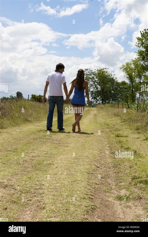 A Couple Walking Down A Dirt Road Holding Hands Stock Photo Alamy