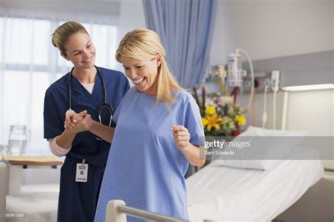Nurse Helping Happy Patient Stand In Hospital Room High Res Stock Photo