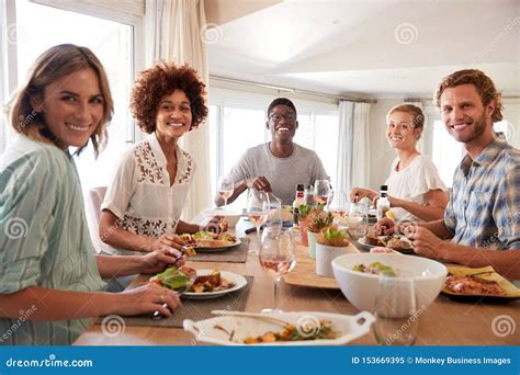 A Group Of Millennial Friends Sitting At A Table Eating Lunch Looking