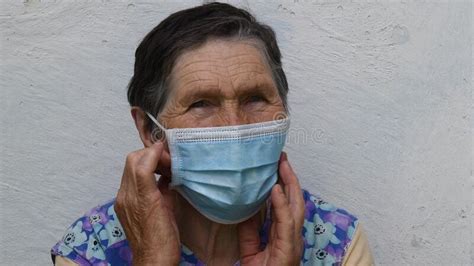 Senior Woman Takes Off And Folds Disposable Mask From Wrinkled Face