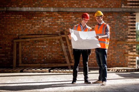 Structural Engineer And Architect Dressed In Orange Work Vests And