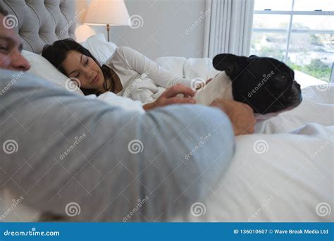 Couple Petting Their Pet Dog In Bedroom Stock Image Image Of Homey