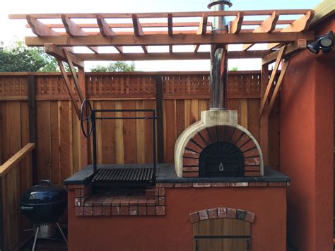 An Outdoor Brick Pizza Oven In A Backyard With A Pergolan Grill On The Side