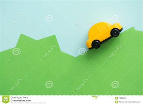 Yellow Car Driving Over Hills With Blue Sky Background Stock Photo