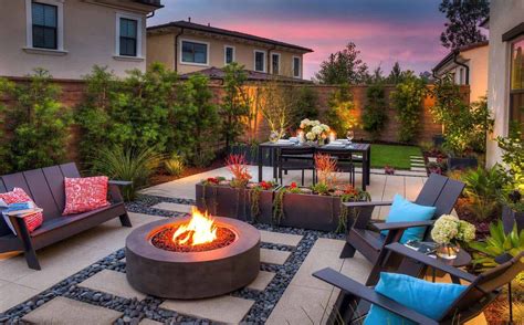 an outdoor fire pit surrounded by chairs and tables in a backyard area