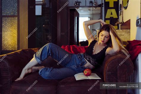 Giovane Donna Sexy Seduta Sul Divano Con Mela E Libro — Occhi Chiusi