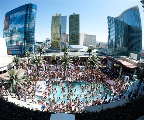 A Large Group Of People Standing Around A Pool In The Middle Of A City With Tall Buildings