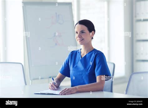 Happy Female Doctor Or Nurse Writing To Clipboard Stock Photo Alamy