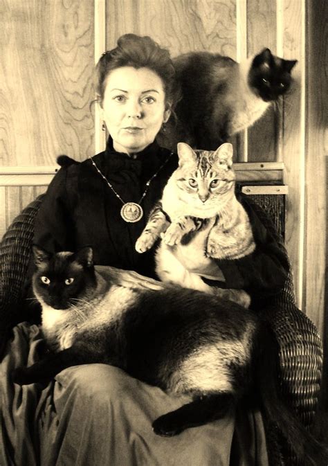 A Woman Sitting In A Chair With Two Cats On Her Lap And Another Cat