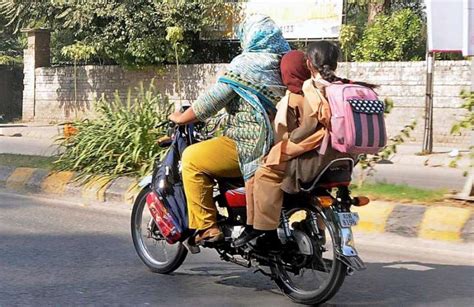راولپنڈی، سکول سے چھٹی کے بعد ایک خاتون موٹر سائیکل پر اپنے بچوں کو گھر لے جا رہی ہے۔