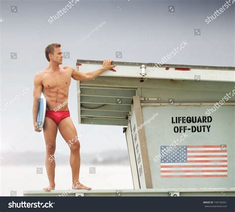 Sexy Male Lifeguard On Top Of Watch Tower Holding Body Board Stock