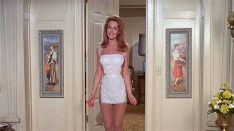 A Woman In A Short White Dress Is Walking Into A Room