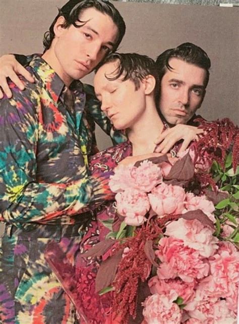 Three Men Standing Next To Each Other With Flowers In Front Of Them And