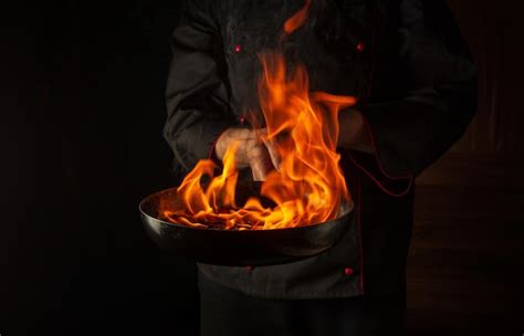 Premium Photo Professional Chef Cooking Food In Pan With Fire Flame