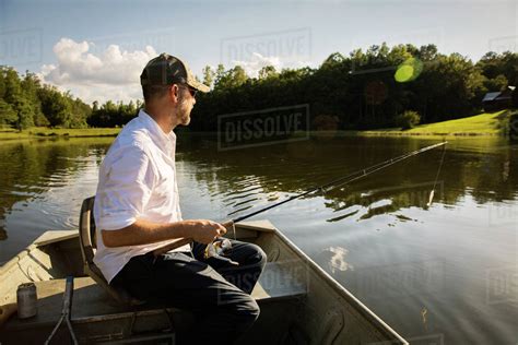 Man Fishing While Sitting In Rowboat On Lake Stock Photo Dissolve