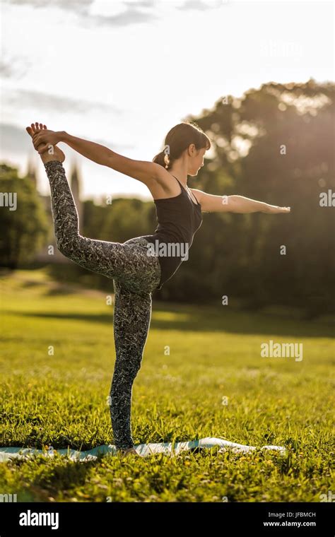 Young Attractive Woman Doing Dancers Yoga Pose Outdoors On Field Stock
