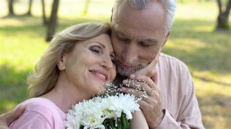 Happy Elderly Woman Holding Flowers Stroking Male Face Mature Love Romance Stock Photo