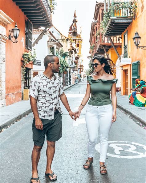 A Man And Woman Holding Hands While Walking Down An Alleyway With