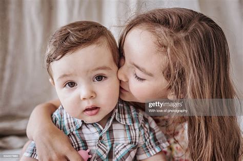 Siblings Big Sister Kissing And Hugging Her Little Brother Photo