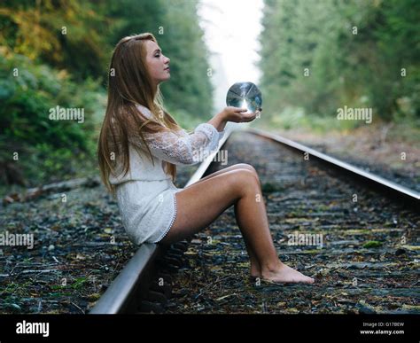 Teenage Girl Sitting On Train Track Holding Crystal Ball Stock Photo