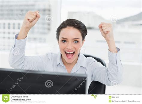 Portrait Of An Excited Businesswoman Clenching Fists In Office Stock