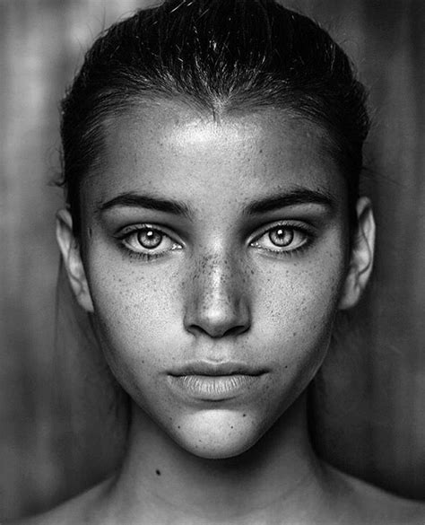 a black and white photo of a woman with freckles on her face looking at the camera