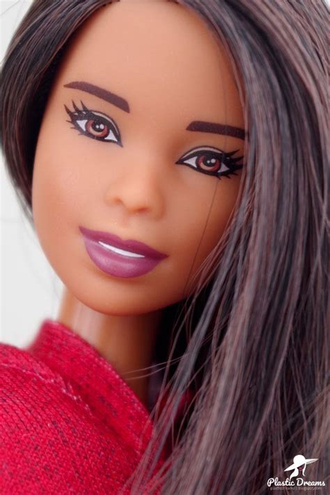 a close up of a doll with long black hair and purple eyeshadow wearing a red sweater
