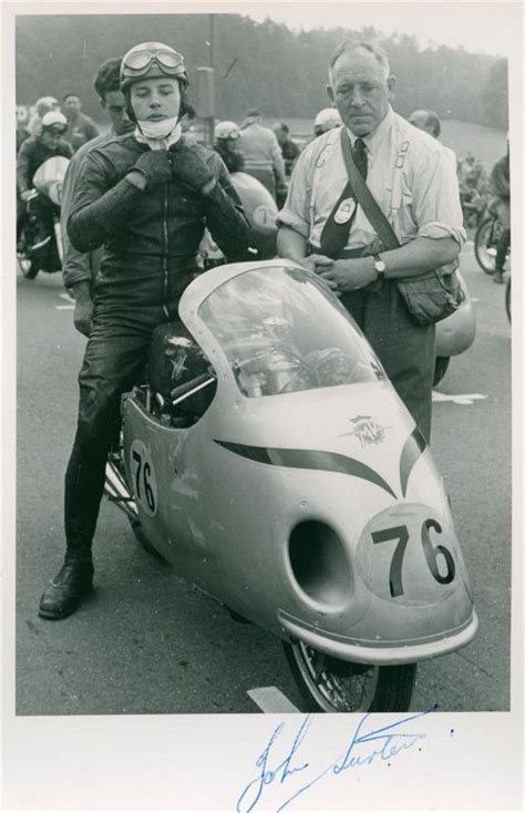 An Old Photo Of Two Men Standing Next To A Motorcycle With The Number
