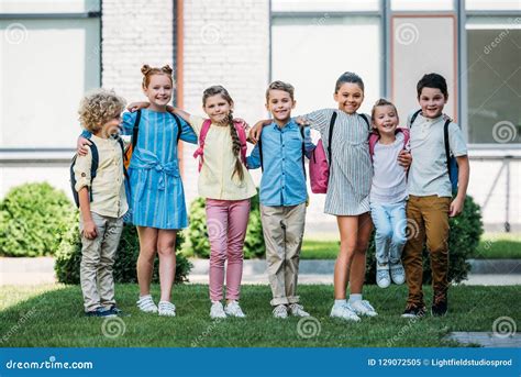 Group Of Adorable Schoolchildren Standing At School Garden And Looking