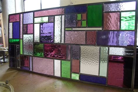 A Stained Glass Window In Purple Pink And Green Squares And Rectangles