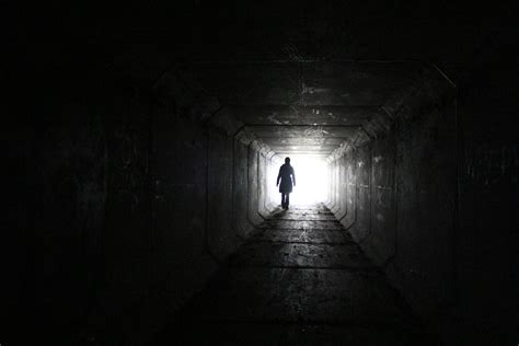 person walking inside dark tunnel with white light on far distanc hd wallpaper wallpaper flare