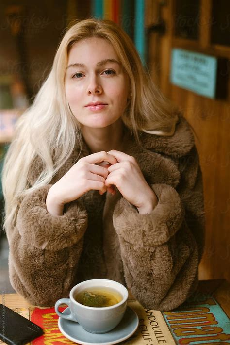 A Woman Sitting At A Table With A Cup Of Tea