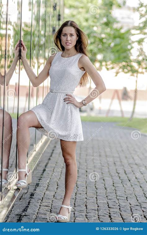 Beautiful Young Girl In A White Summer Dress Near A Showcase With