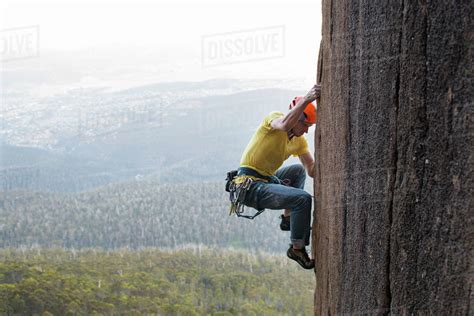 Side View Of A Male Rock Climber Moving His Feet Up As He Works His Way
